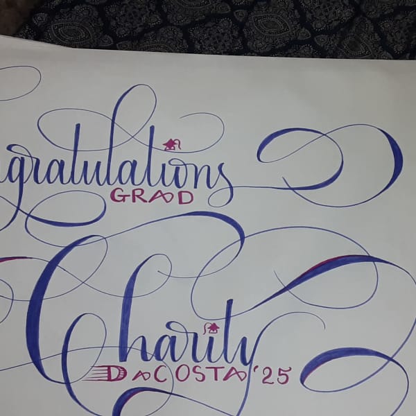 Decorative calligraphy reading "Congratulations Grad" and a name on white paper