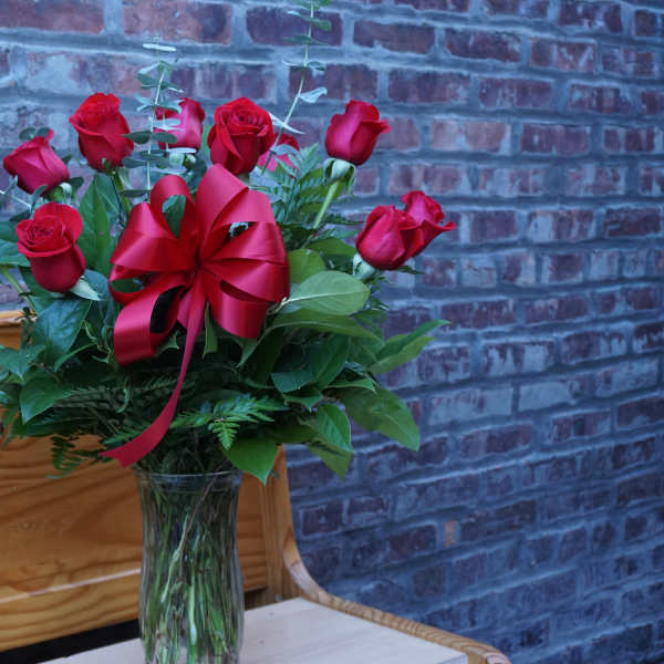 Red roses in a clear glass vase with a red ribbon bow