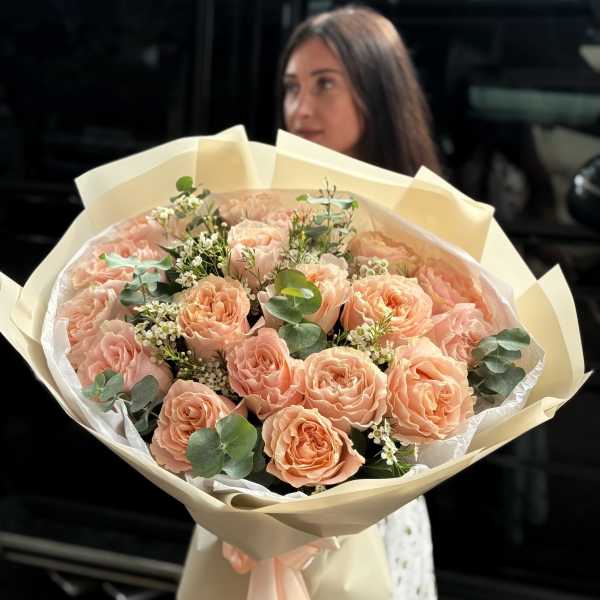Peach rose bouquet wrapped in cream paper with a satin ribbon