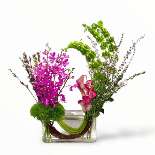 Pink orchids and calla lilies in a clear rectangular vase