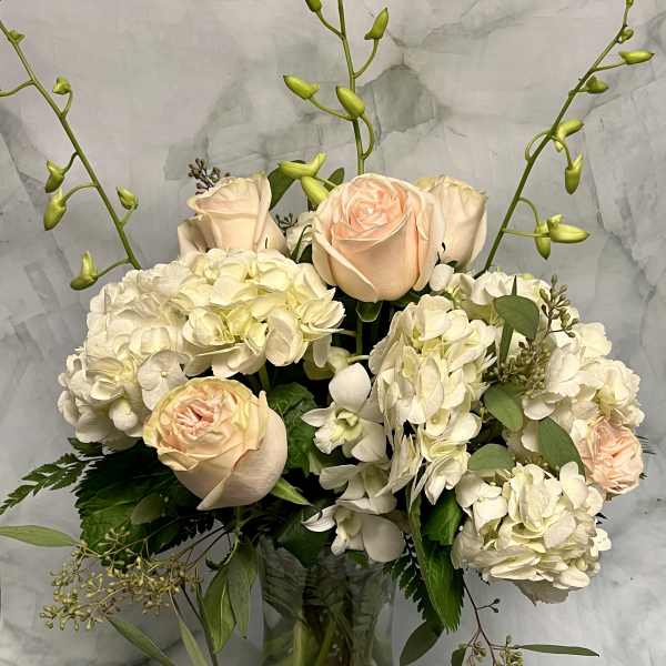 Cream and blush roses with white hydrangeas in a glass vase