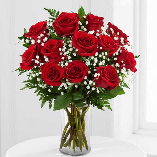 Red roses with baby's breath in a clear glass vase