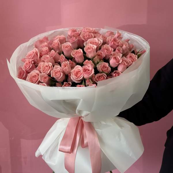 Large bouquet of pink roses wrapped in white paper with a pink ribbon