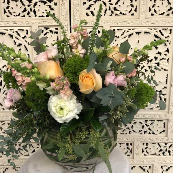 Mixed bouquet of peach and pink roses in a glass vase