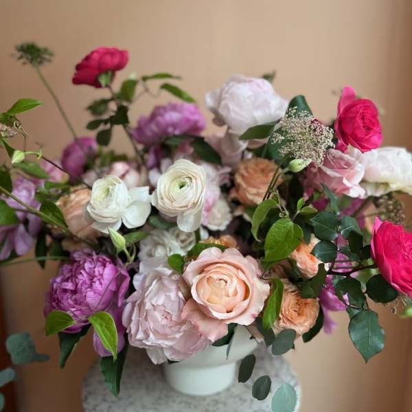 Mixed bouquet of pink, white, and peach flowers in a white vase