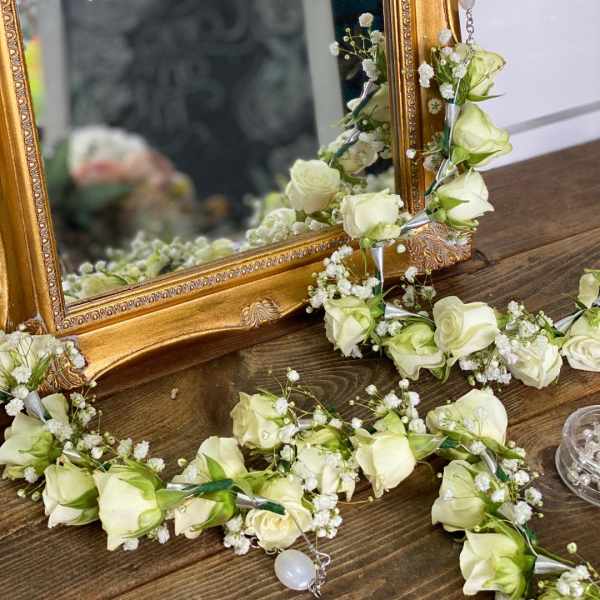 White rose garlands draped around an ornate gold mirror