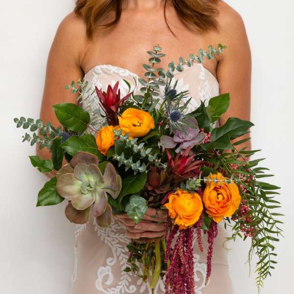 Bride holding a bouquet with orange flowers and succulents