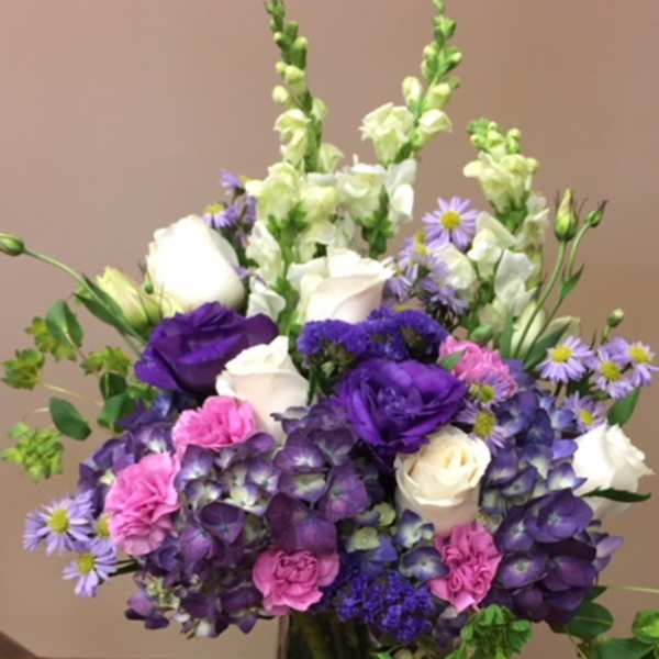 Purple, white, and pink bouquet in a clear glass vase