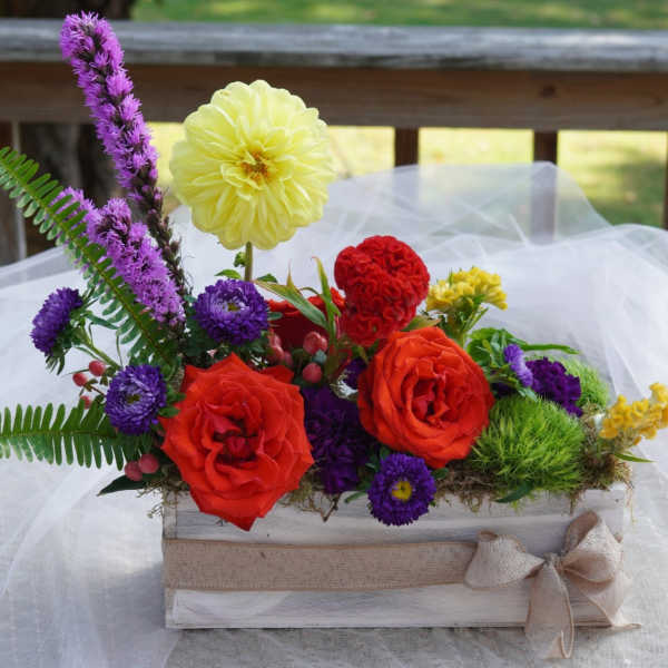 Colorful flower arrangement in a white wooden box with a burlap bow