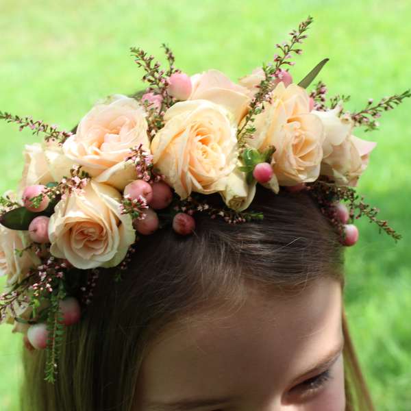 Floral crown of pale peach roses with pink berries on a girl's head