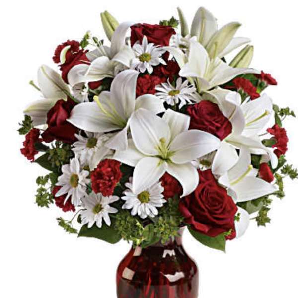 Red roses and white lilies arranged in a red glass vase