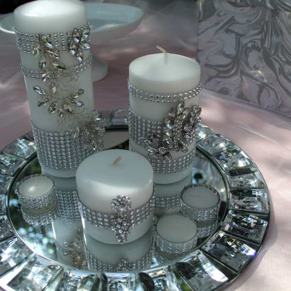 White candles decorated with rhinestones on a mirrored tray