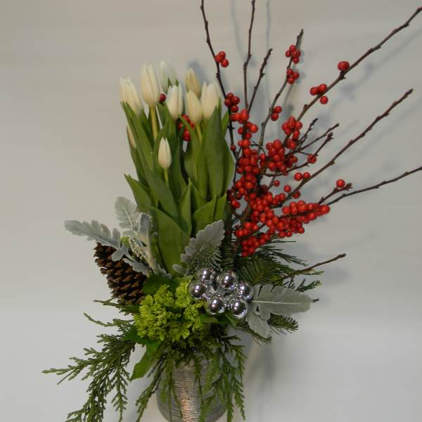 White tulips in a silver vase with red berries and pinecones