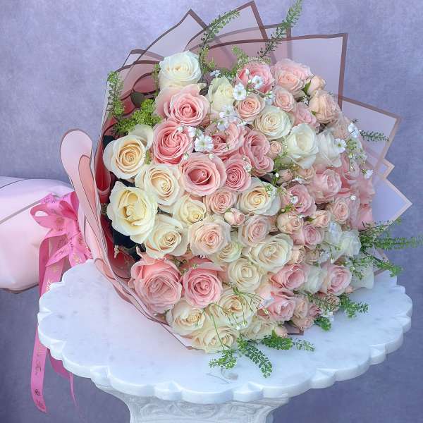 Large bouquet of pink and cream roses wrapped in pink paper