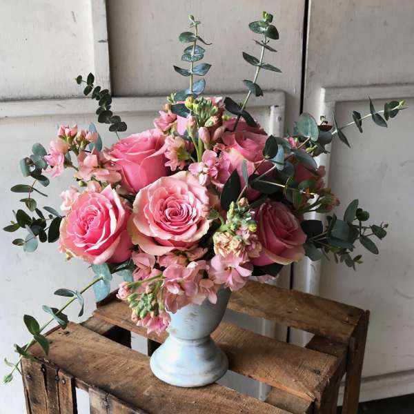 Pink roses and small pink flowers in a white vase with eucalyptus