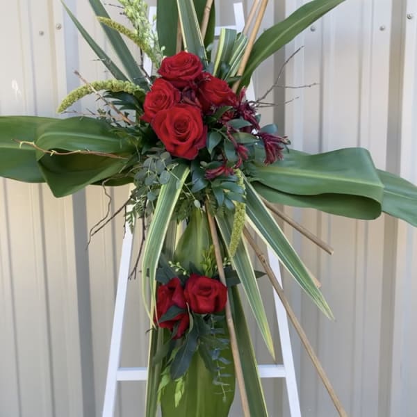 Tall standing floral spray with red roses and large tropical leaves