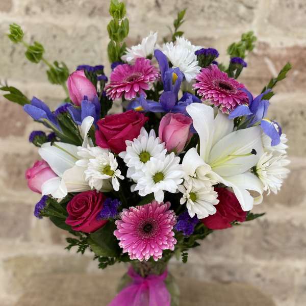 Bouquet of pink roses, white lilies, and daisies with purple accents