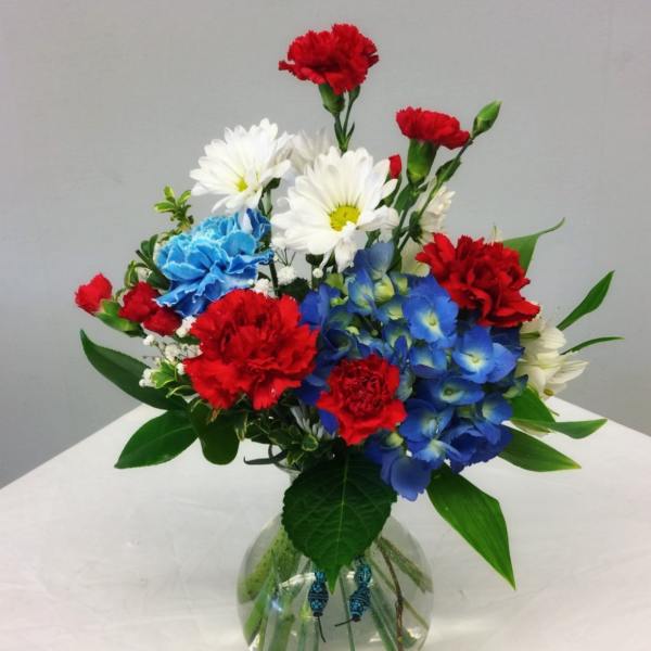 Colorful bouquet of carnations and daisies in a round glass vase