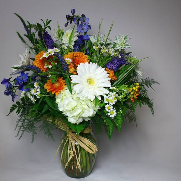 Mixed bouquet in a glass vase with white, orange, and blue flowers