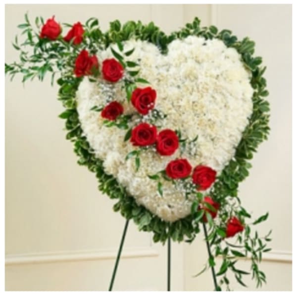 Heart-shaped white floral spray with red roses on a stand
