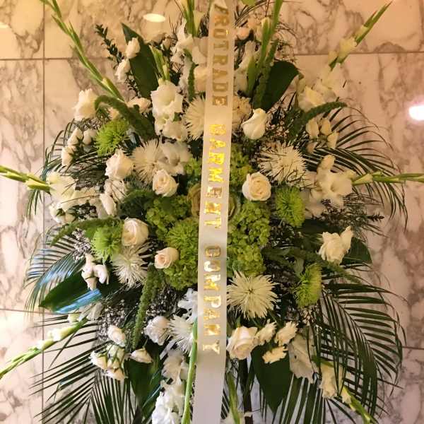 Large white funeral spray with a condolence ribbon