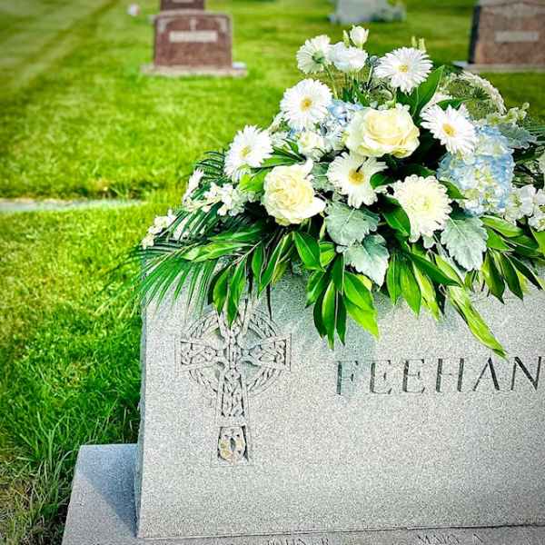 White and pale blue floral arrangement on a gravestone
