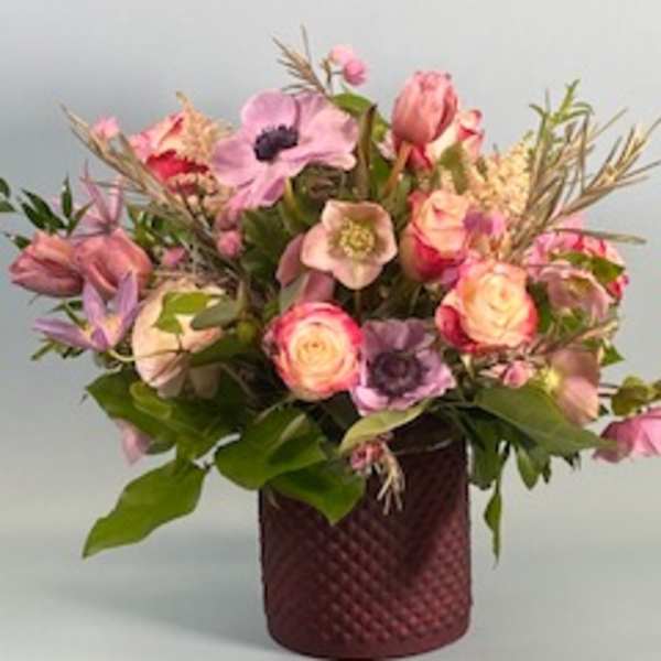 Mixed pink and purple flower arrangement in a textured burgundy vase