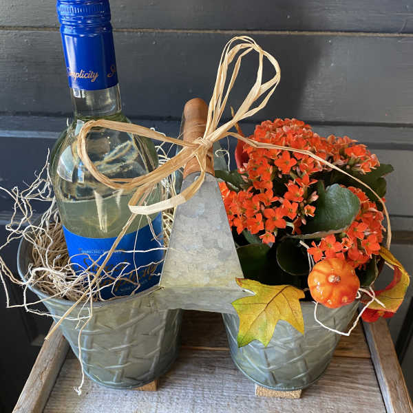 Gift basket with a wine bottle and orange potted flowers