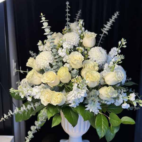 White roses and pompom mums in a white pedestal vase