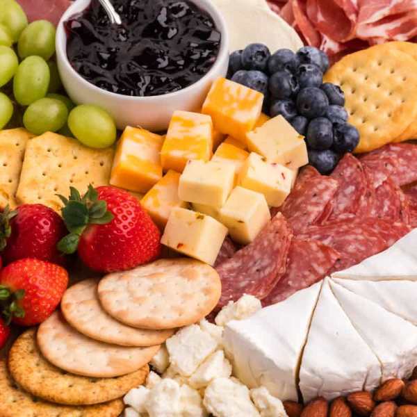 Charcuterie board with cheese, crackers, fruit, and salami