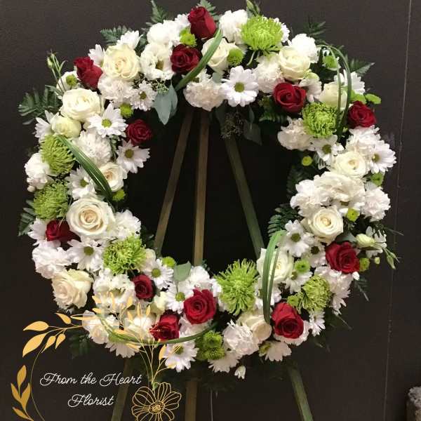 Circular funeral wreath of red and white flowers on a stand