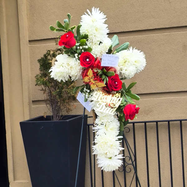 Standing floral tribute with red roses and white chrysanthemums on an easel
