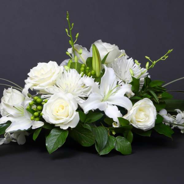 White floral centerpiece with roses and lilies on a dark background