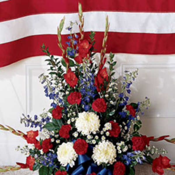 Red, white, and blue floral arrangement with ribbon in a vase