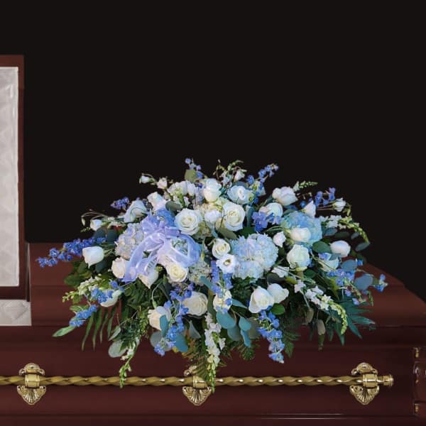 White and blue floral arrangement on a casket