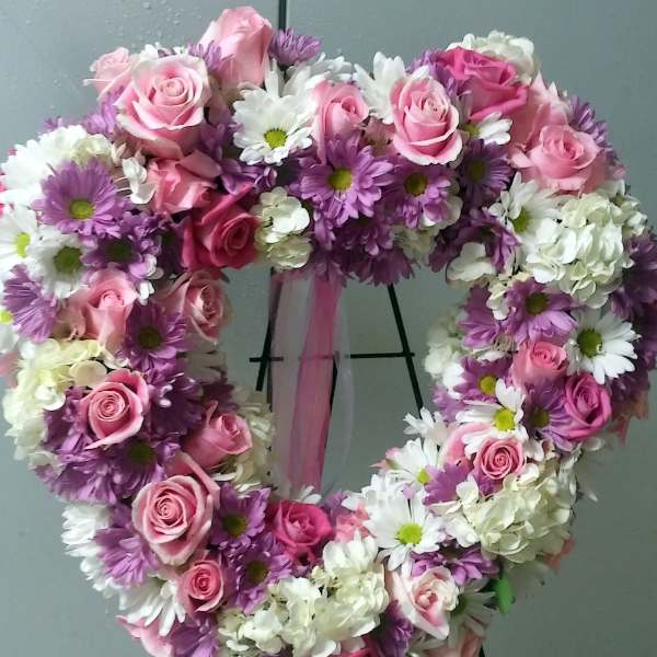 Heart-shaped floral wreath with pink roses and white and purple daisies