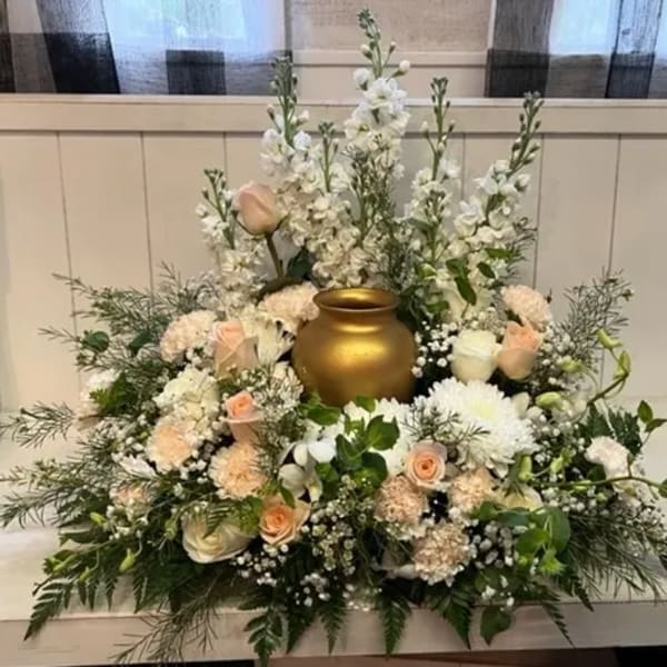 White and blush floral arrangement around a gold urn