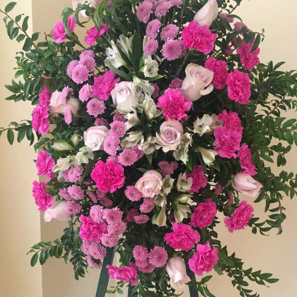 Standing floral spray with pink and white flowers on a tripod easel