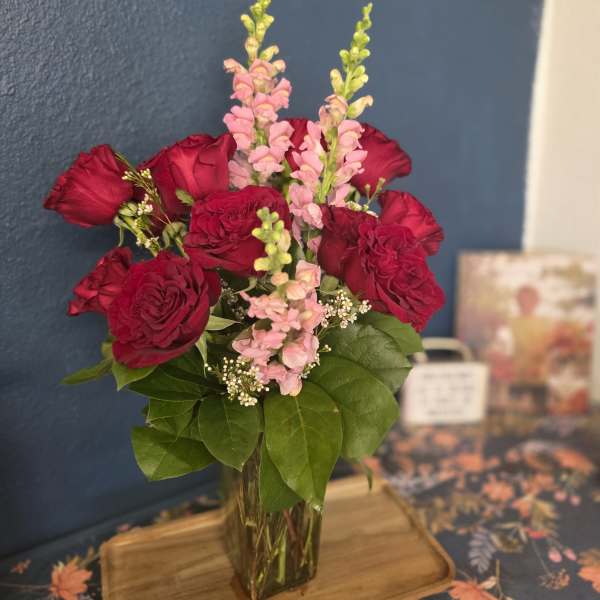 Red roses and pink snapdragons in a clear glass vase