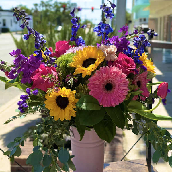 Bright mixed bouquet with sunflowers, pink gerberas, and purple blooms in a vase