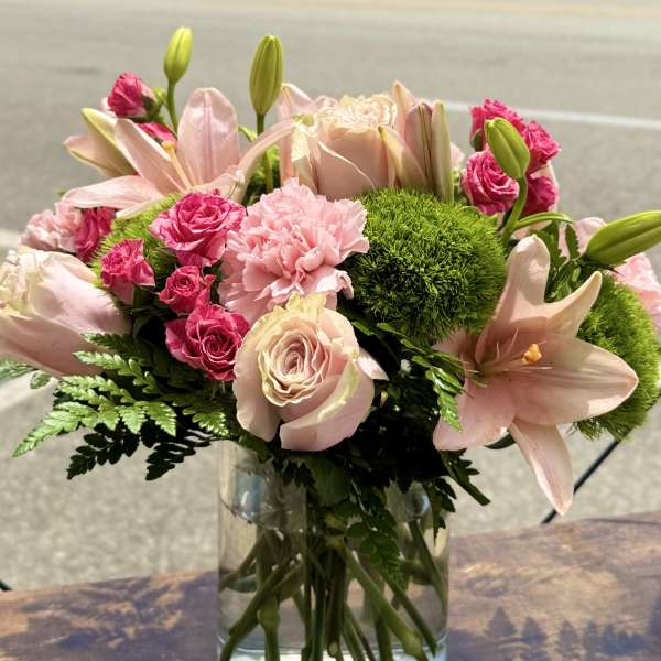 Pink roses and lilies arranged in a clear glass vase