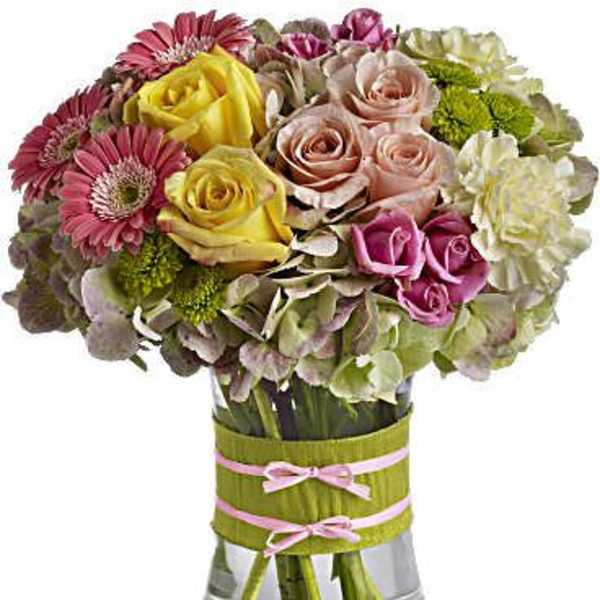 Mixed bouquet of roses, gerbera daisies, and hydrangeas in a glass vase