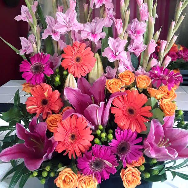 Tall mixed bouquet with pink gladiolus, gerbera daisies, and orange roses