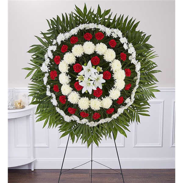 Circular funeral wreath with red and white flowers on a stand
