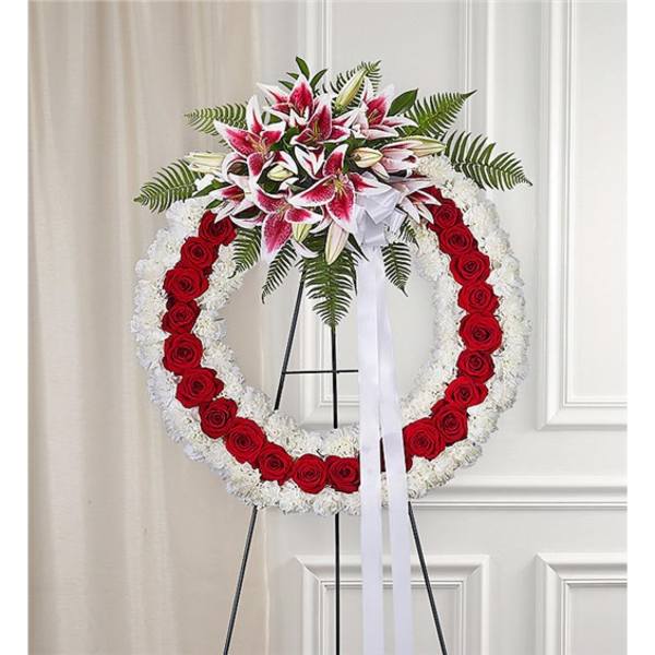 Standing funeral wreath with red roses, white flowers, and pink lilies