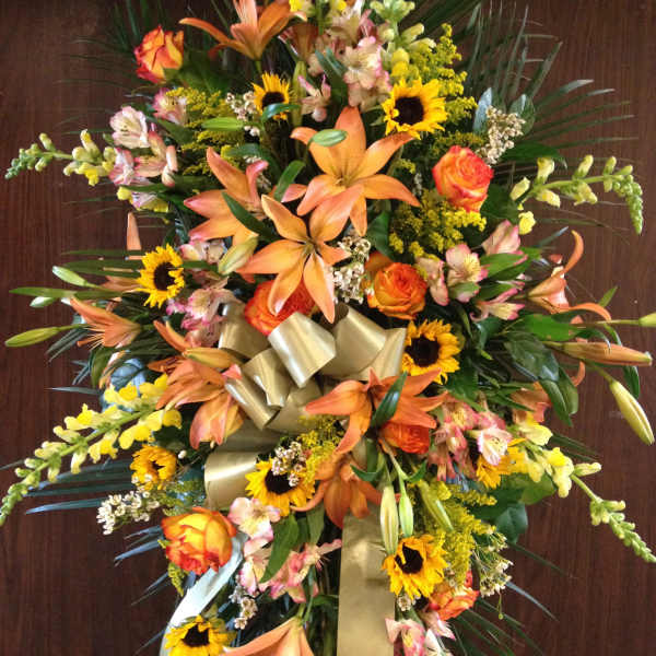 Large standing floral spray with orange lilies, sunflowers, and roses