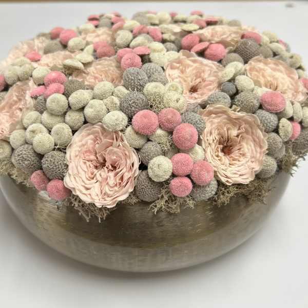 Round floral arrangement in a low metallic bowl with blush and pink blooms