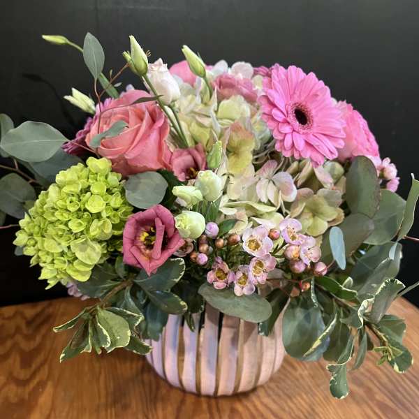 Pink and green mixed flower arrangement in a striped vase
