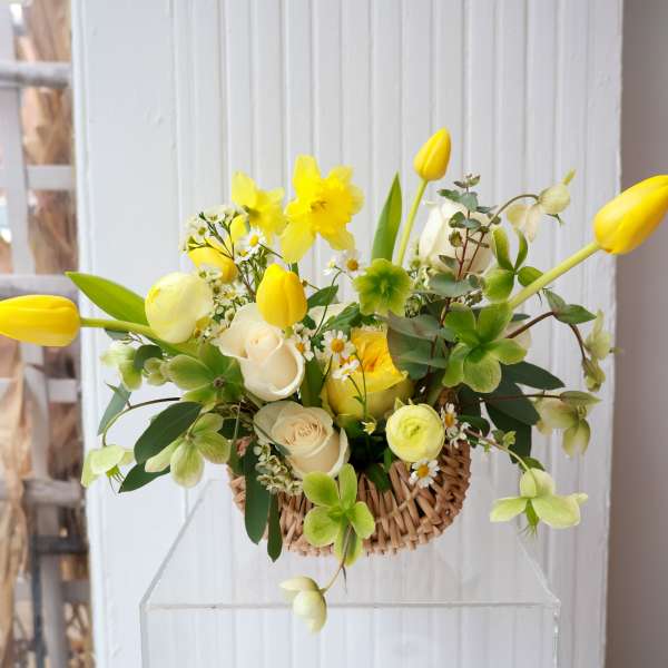 Yellow tulips and white roses in a woven basket arrangement