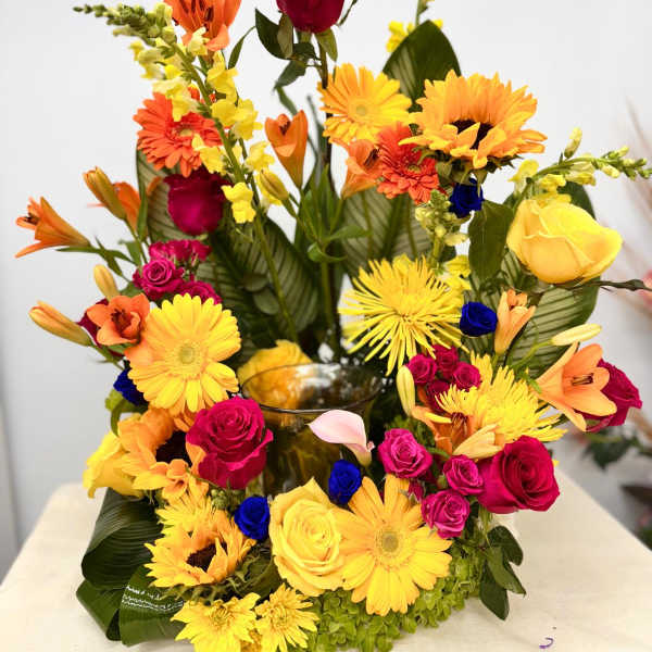 Bright mixed bouquet with roses, lilies, gerberas, and sunflowers in a vase